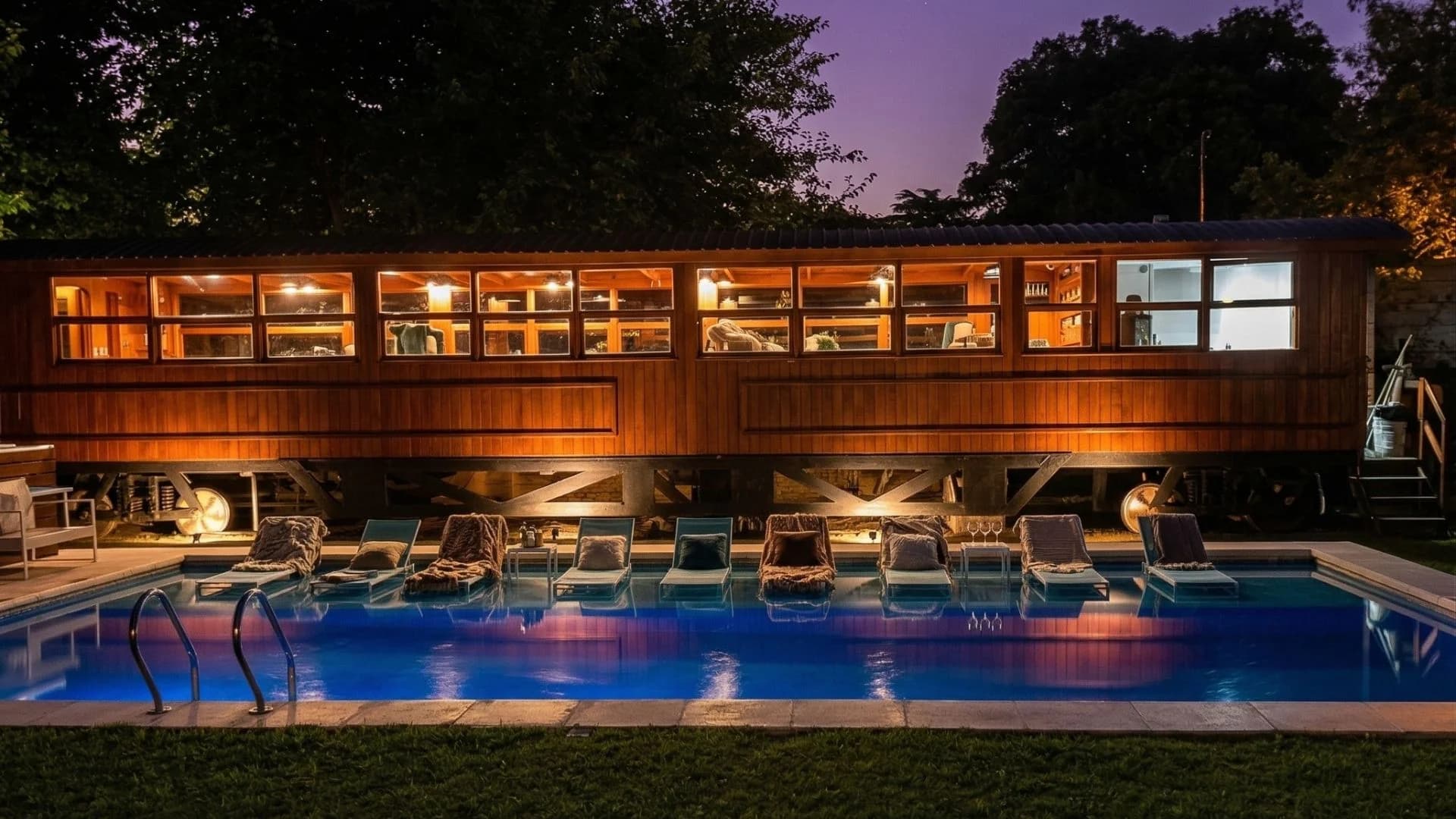 Vagón comedor y piscina iluminada de noche